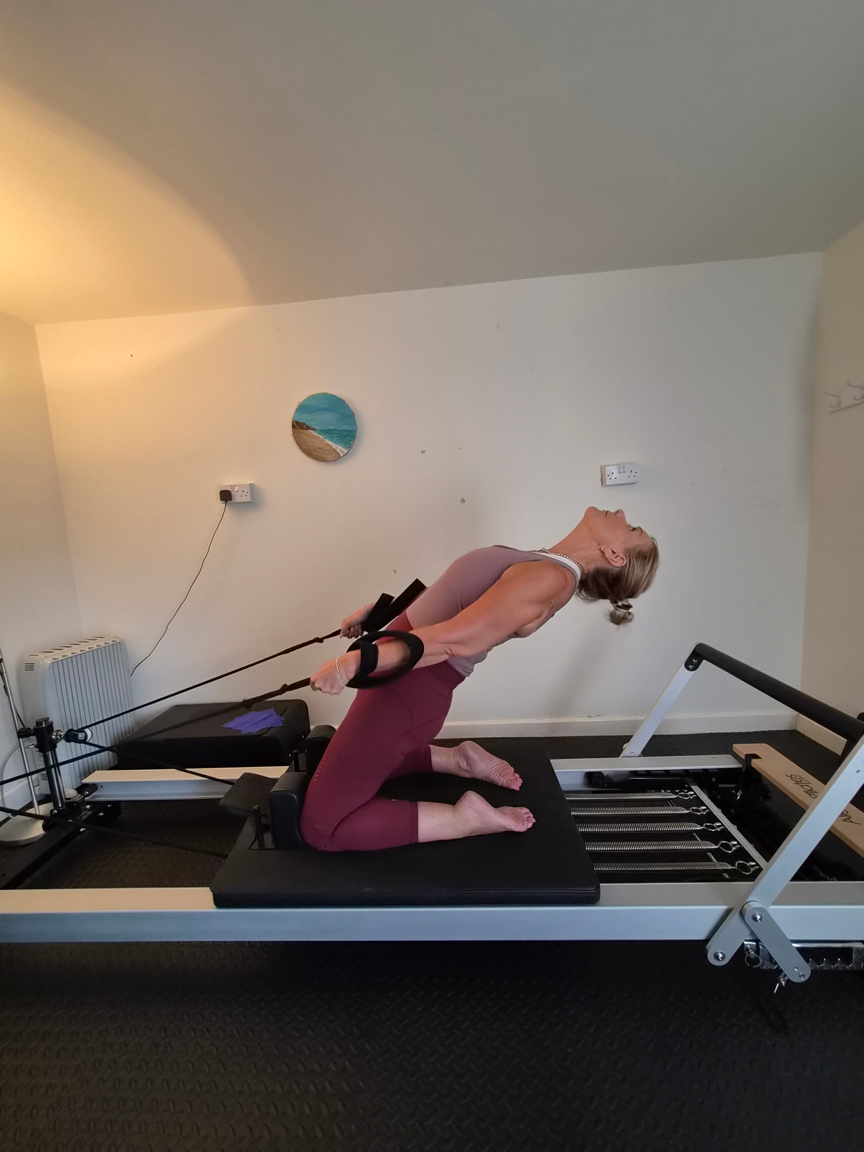 Client kneeling on a reformer working through a chest expansion