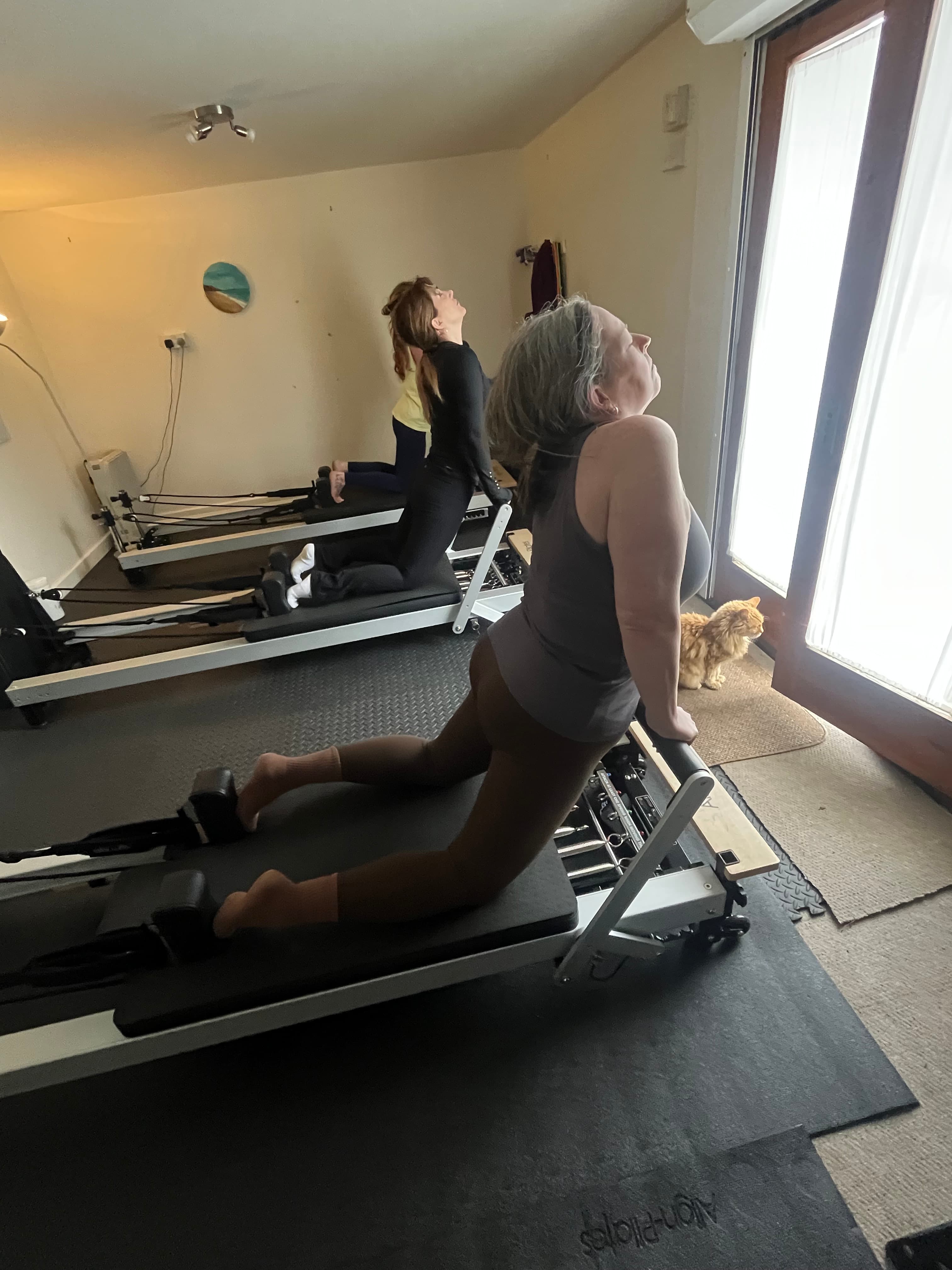 Instructor supporting a client through a reformer exercise one to one