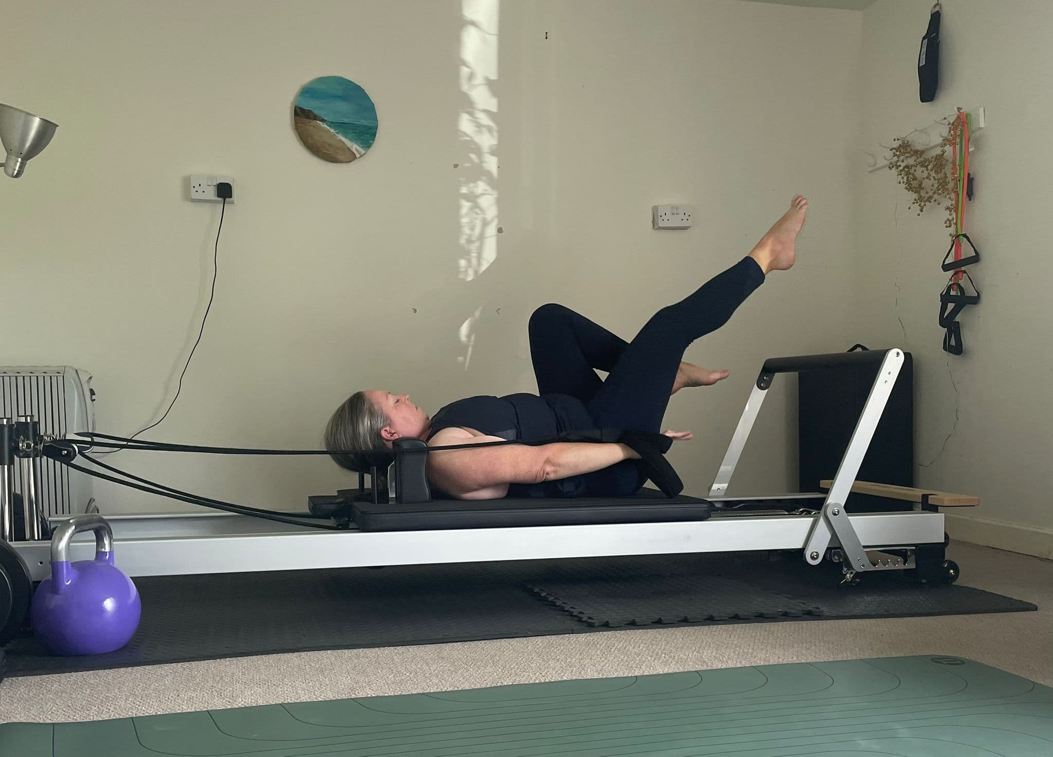 Client lying on the reformer working through a leg and core exercise